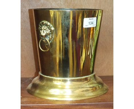 A brass wine cooler of tapering form having applied lion mask and ring handles, 17cm diameter, 19.5cm high.