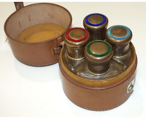A vintage perfume bottle set including four glass wedge-shaped perfume bottles and stoppers, with guilloche enamel twist meta