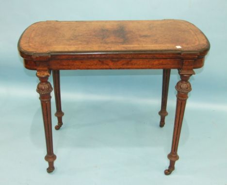 A Victorian burr walnut card table, the fold-over top with metal beaded border raised on carved and fluted turned legs with c