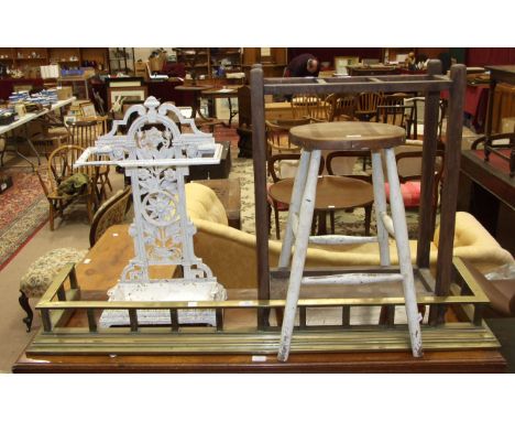 A painted wrought iron stick stand, 68cm high, a brass fire kerb, 134cm wide, a wooden three-division stick stand and a stool