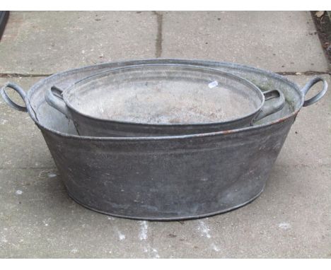 A vintage oval galvanised tin two handled bath 65 cm long (excluding handles) x 48 cm wide x 24 cm high, together with a simi