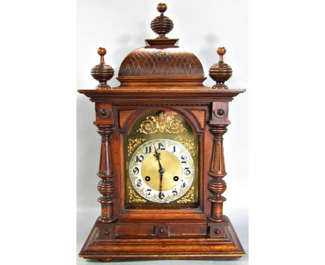 19th century German walnut mantle clock enclosing an arched brass dial with silvered chapter ring, the case with carved detai