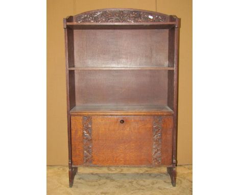 A slender oak freestanding open bookcase with carved acorn and oak leaf detail and fixed shelves over a Canterbury with fall 