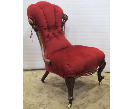 A Victorian nursing chair with buttoned upholstery and show wood frame raised on scrolled cabriole forelegs with ceramic cast