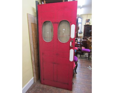A 19th century country house green baize door, (but upholstered in red!) with brass stud work detail and ceramic finger plate