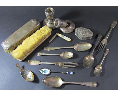 Seven pieces of silver Georgian flatware, a caddy spoon, a small squat candlestick, three silver backed brushes and hand mirr