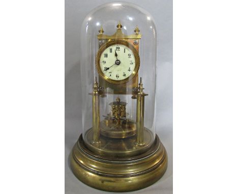 A brass anniversary clock raised on turned column supports, set beneath a glass dome 