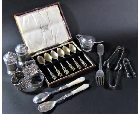 A mixed selection of silver tableware including a three piece condiment set, three sugar tongs, three napkin rings, a single 