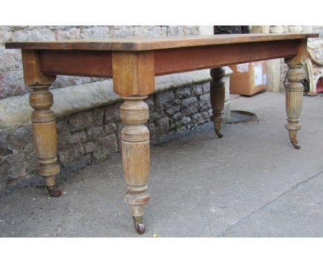 A Vintage mixed wood kitchen table with rectangular pine top raised on four turned and reeded legs with brass caps and cerami