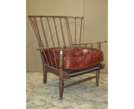 A vintage stained beechwood stick and wing back armchair with sprung seat and later associated leather cushion 