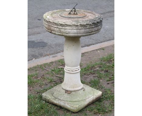 A garden sundial, the circular dial with pierced gnomon set on a two sectional composition stone base/support with relief det