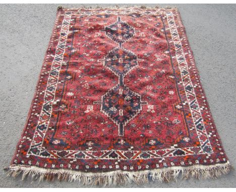 A Middle Eastern carpet with triple linked lozenge on a red ground, 190cm x 140cm approx. 