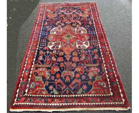 An early 20th century Baktia carpet with large stylised flowers on a blue ground 