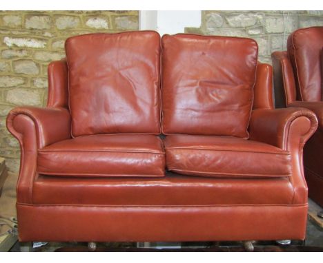 A contemporary brown leather upholstered two seat wing back sofa with rolled arms and loose seat cushions together with a mat