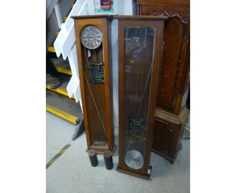 Two oak Synchronome master clock cases each with a movement, dial and pendulum, 127cm high and 129cm high 