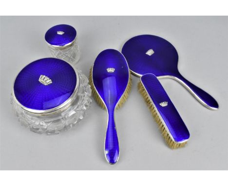 An early 20th century silver and enamel mounted matched dressing table set, comprising a hand mirror, two brushes, a cut glas