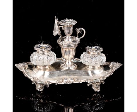 A Victorian silver desk ink stand, oval form with cast foliate rim, scrolled feet and silver-mounted glass inkwells with cent