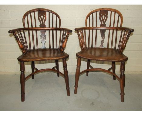 A pair of 19th century yew wood comb-back Windsor chairs, with shaped elm seats and crinoline stretchers, one with damaged sp