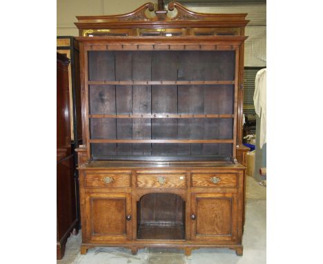 A Georgian oak dresser, the upper part with moulded cornice, above three shelves with iron cup hooks, the lower part with thr