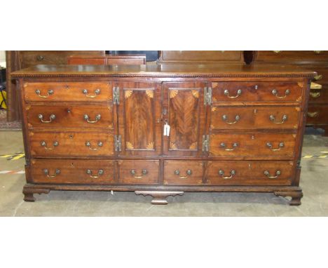A large Georgian mahogany dresser base, the top with moulded and inlaid edge above a pair of central cupboard doors, flanked 