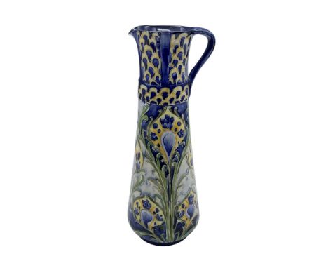 A small slender pitcher in hand painted blue, yellow, ad green. Beautifully decorated in an Art Nouveau stylized peacock feat