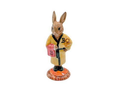 Hand modelled and hand painted figure of a bunny ready for a bath. Yellow robe with a black trim and sash. Holding a red towe