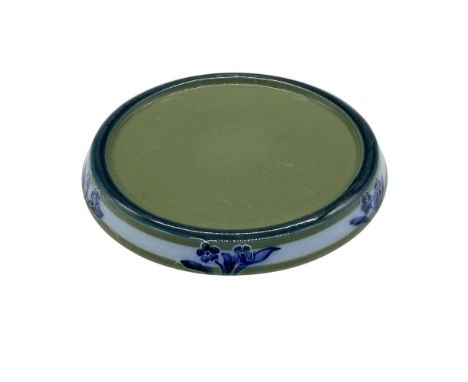 An English pottery round stand in a blue and green glaze. decorated with whimsical blue five-petal flowers in a tubeline outl