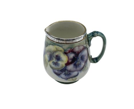 A creamer with a silver plated rim decorated with yellow and purple pansies. A floral pattern designed by William Moorcroft f