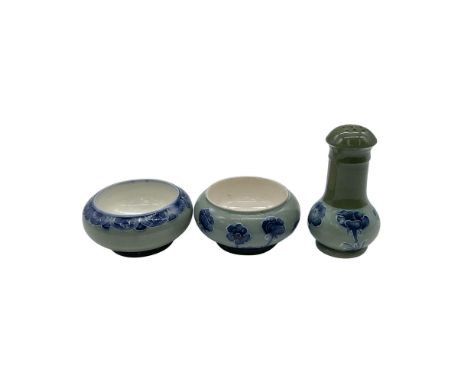 A collection of English pottery in a green glaze decorated with blue blossomed poppies. Includes a salt cellar with a floral 