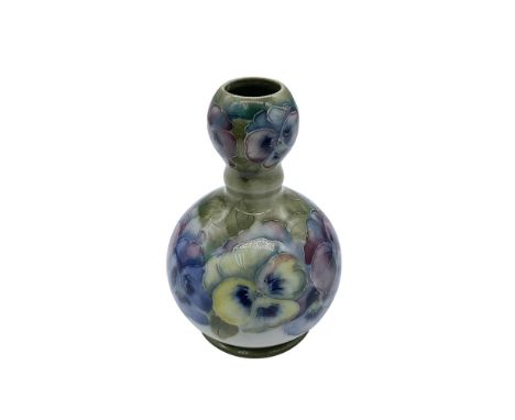A small bottle-shaped vase decorated with yellow and purple pansies. A floral pattern designed by William Moorcroft for James