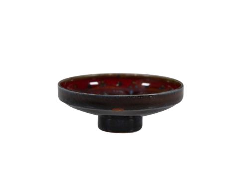 A ruby red ring dish features blue floral artwork in its interior and stands on a delicate foot. Royal Doulton backstamp. Dim