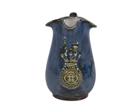 A small blue glazed pitcher with a flower shaped mouth displays the Royal Doulton logo in its center. Royal Doulton backstamp