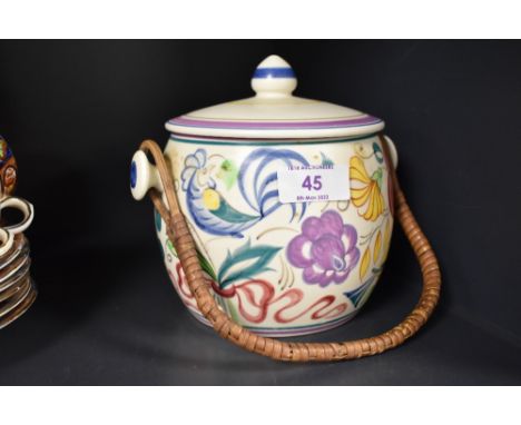 A Poole Pottery hand-decorated biscuit barrel, with finial topped cover and rattan over handle, the cover and body decorated 