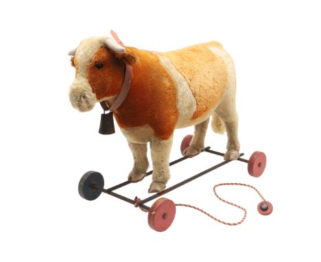 UNUSUAL STEIFF PULL ALONG COW. A large early 20thc Steiff soft toy Cow, with leather horns and hoofs and mounted on a metal f