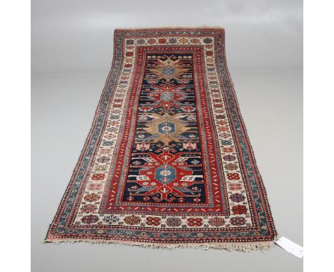 A SOUTH CASUCASIAN RUNNER, 1900. he indigo field with a column of polychrome medallions enclosed by ivory borders of stylised