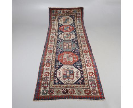A CAUCASIAN RUNNER, CIRCA 1900. the indigo field with a column of octagons containing stylised plants enclosed by ivory borde
