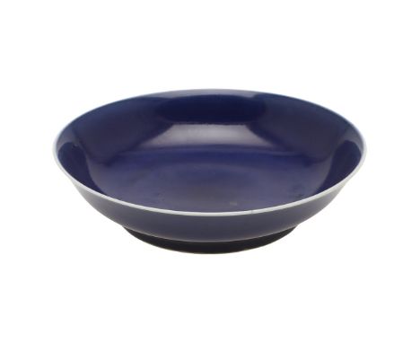 CHINESE KANGXI MONOCHROME DISH. Kangxi mark and period (1662-1722), a blue glazed circular dish, the rounded sides rising fro