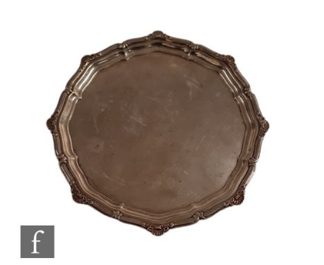 A hallmarked silver card waiter of plain form with shell and scroll border, weight 13oz, diameter 22cm, raised on three paw f