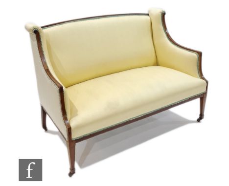 An Edwardian line inlaid mahogany three seater sofa with scroll arms on square tapering legs, upholstered in pale yellow, wid