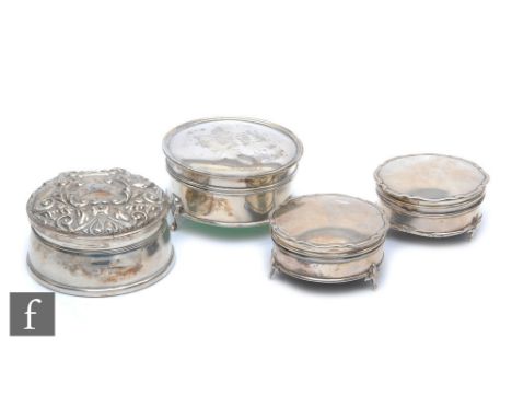 Four hallmarked silver circular trinket boxes, three of plain form and each raised on three strut feet, with a similar foliat