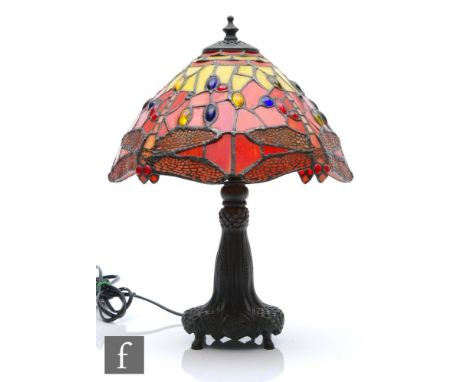 A reproduction Tiffany style table lamp, the shade decorated with a mosaic dragonfly design in tones of red and yellow, to an