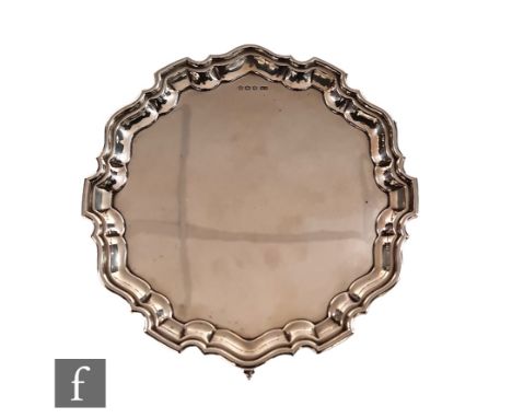 A hallmarked silver circular salver of plain form, weight 17.5oz, diameter 25cm, terminating in scalloped border and raised o