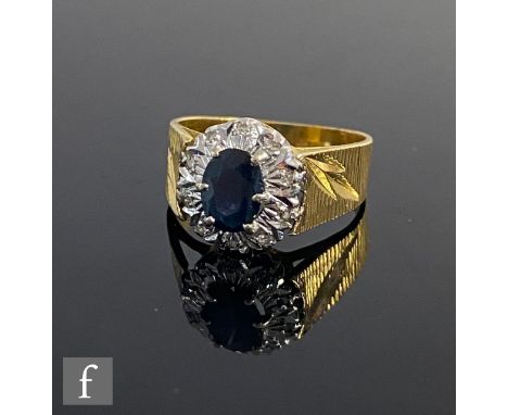 An 18ct sapphire and diamond cluster ring, central sapphire within a border of diamonds to wide bark effect shoulders, weight