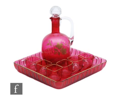 A late 19th Century ruby glass liqueur set comprising a shouldered spirit jug and six small loop handles cups, all relief pas