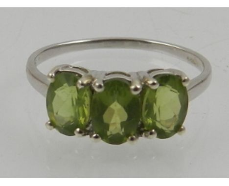A 9 carat white gold and peridot three stone ring. 