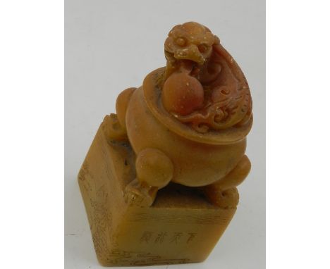 A Chinese soapstone seal, the finial carved with a dragon with pearl of wisdom seated on a cauldron. H.11.5cm