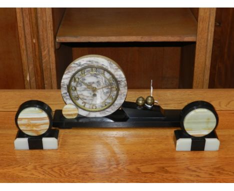 An Art Deco marble onyx and brass mounted clock and garniture, the dial having Roman numerals, striking bell. 