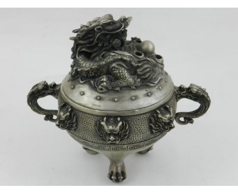 A Chinese white metal incense burner, having twin dragon handles and dogs of Fo masks to waist with Greek key border, the fin