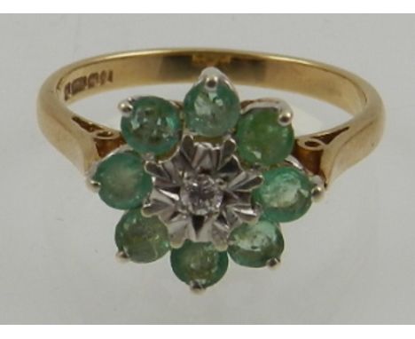 A 9 carat yellow gold, emerald and diamond set floral cluster ring. 