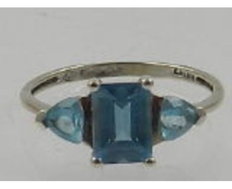 A 9 carat white gold and sky blue topaz ring, set central emerald cut stone flanked by two trillion cut stones. 